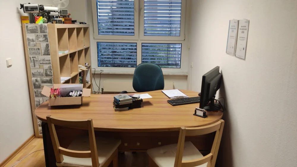 Kundenraum R 215 im 2. OG: Schreibtisch mit Monitor, Regal mit Schmalfilmkameras, Projektor und Filmspulen